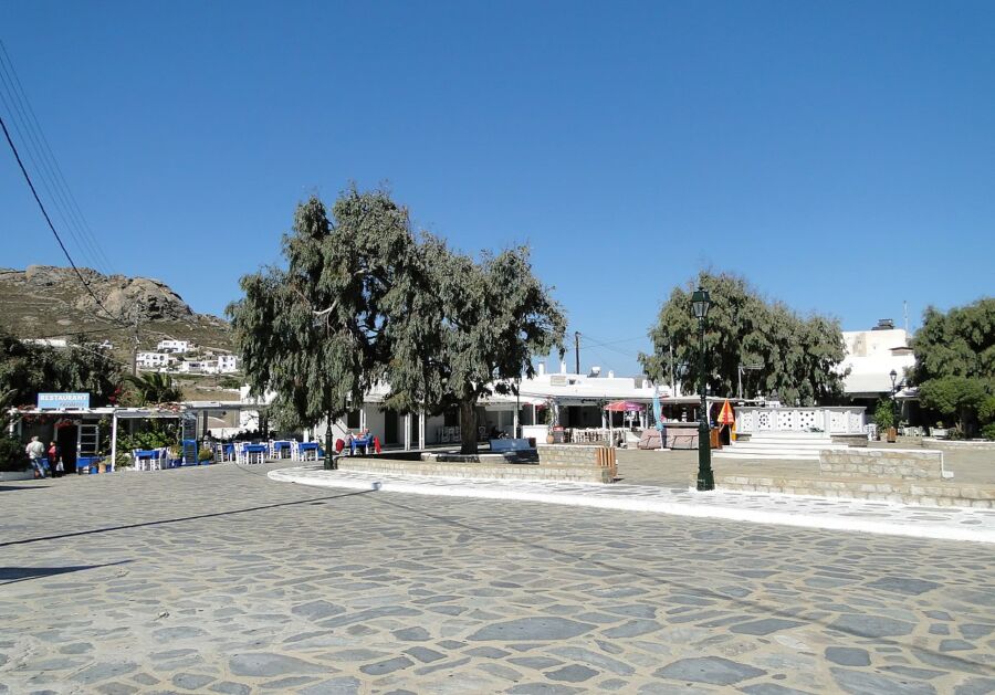 Picturesque scene of Ano Mera, Greece, featuring a small town with several people strolling around.