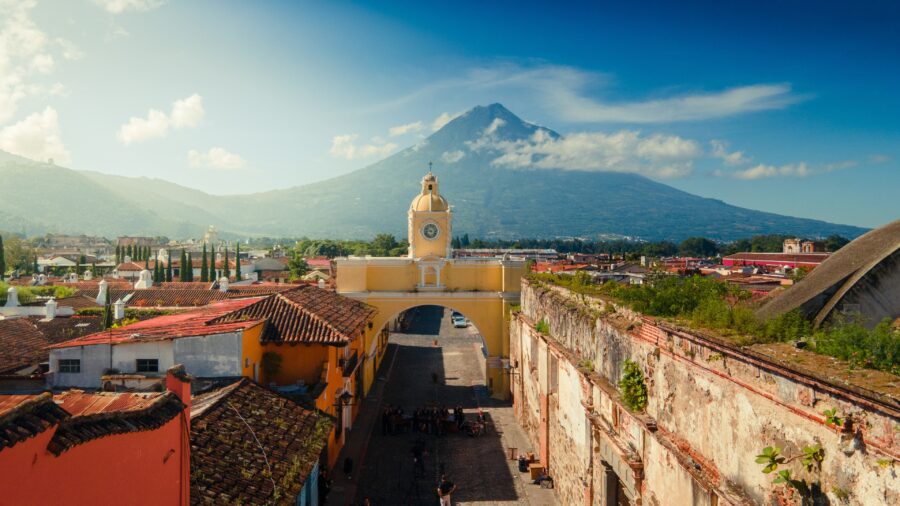 View of Arco de Santa Catalina, Antigua, Guatemala, with volcano in the background.