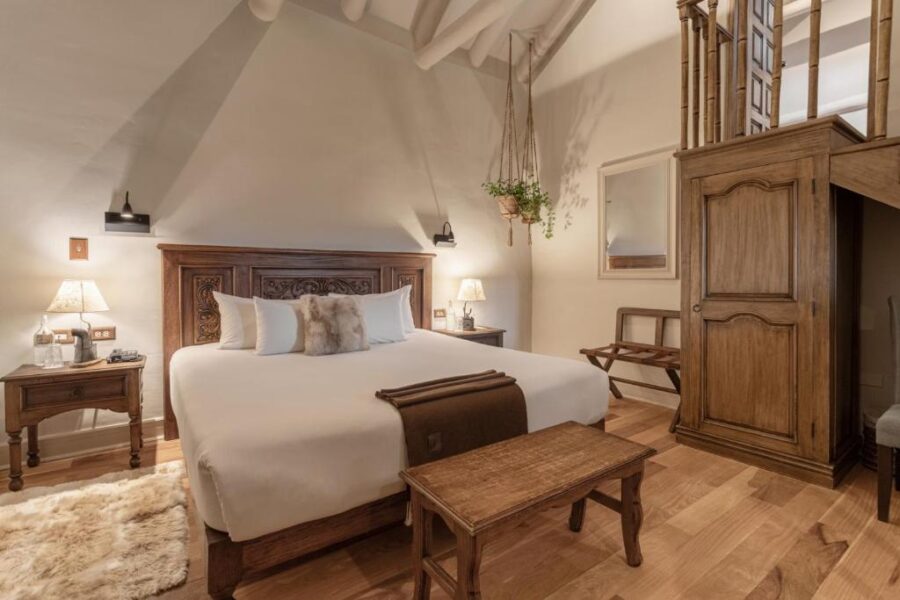 Interior of a bedroom at Antigua Casona San Blas, showcasing a wooden staircase and a comfortable bed.