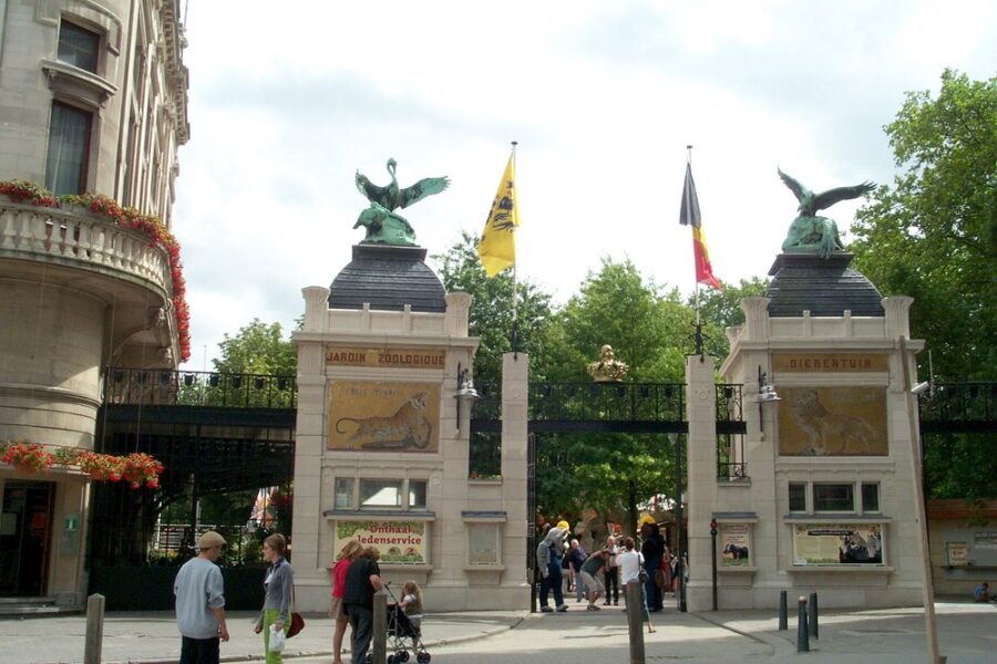 Large building at Antwerp Zoo features a grand gate and a prominent statue of a bird in front.
