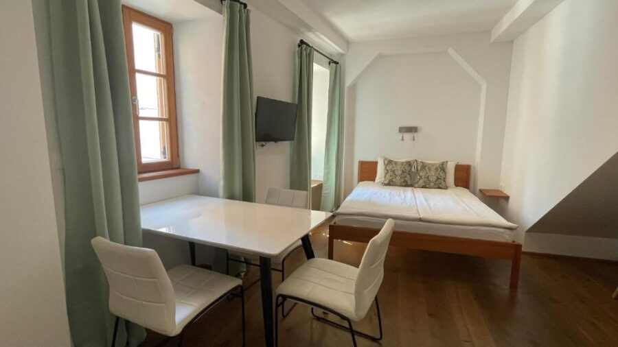 Cozy room with a bed, table, and chairs, part of Apartments Fonda House in Piran, Slovenia.