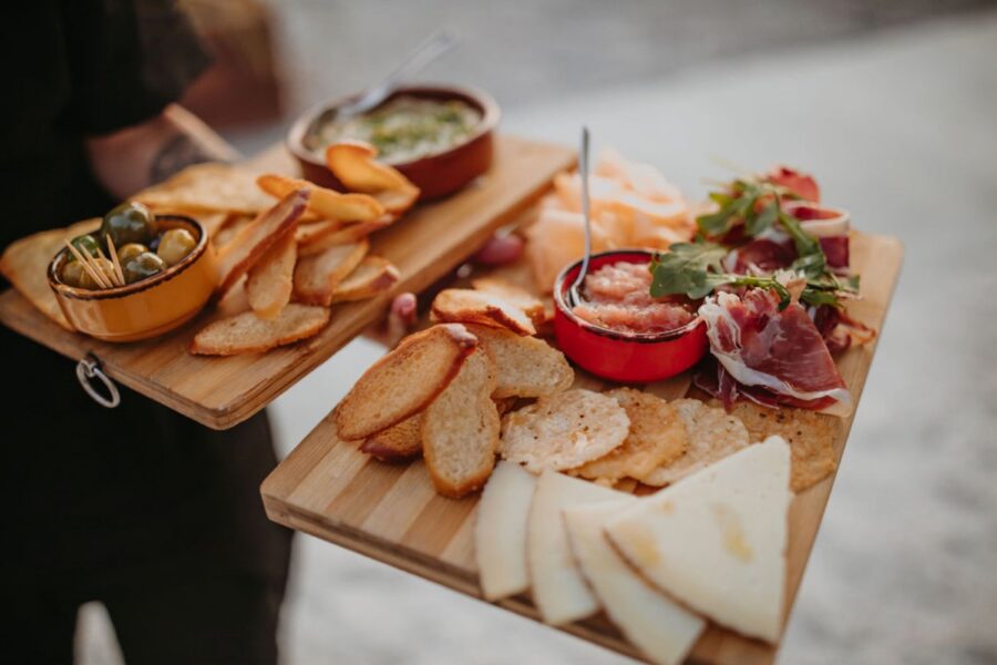 Spanish tapas with crispy snacks, cured meats, olives, and dip on wooden platters.