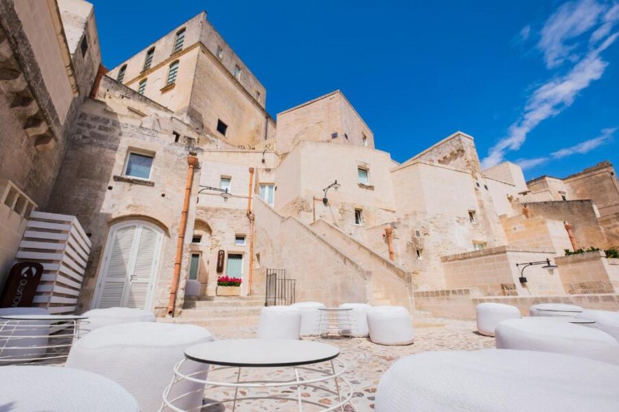Courtyard of Aquatio Cave Luxury Hotel & Spa in Matera, featuring elegant white furniture amidst a serene setting.