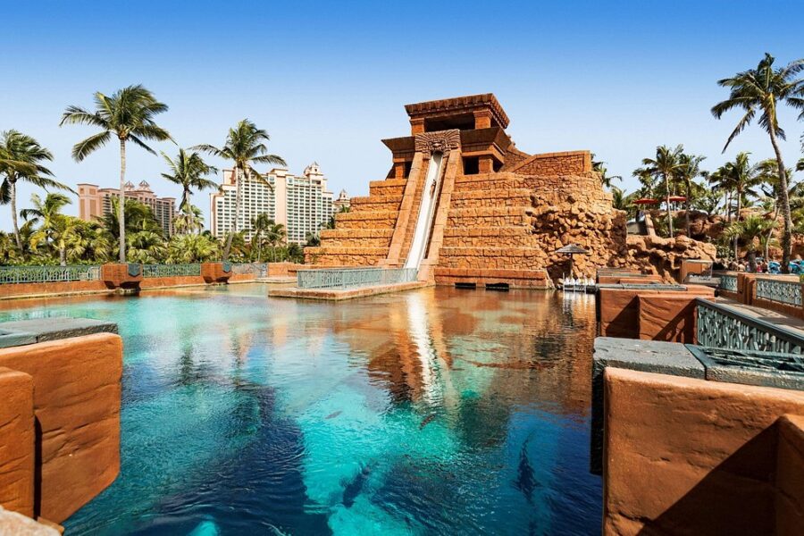 Vibrant water slide in a pool surrounded by lush palm trees at Aquaventure water park in Nassau, Bahamas.