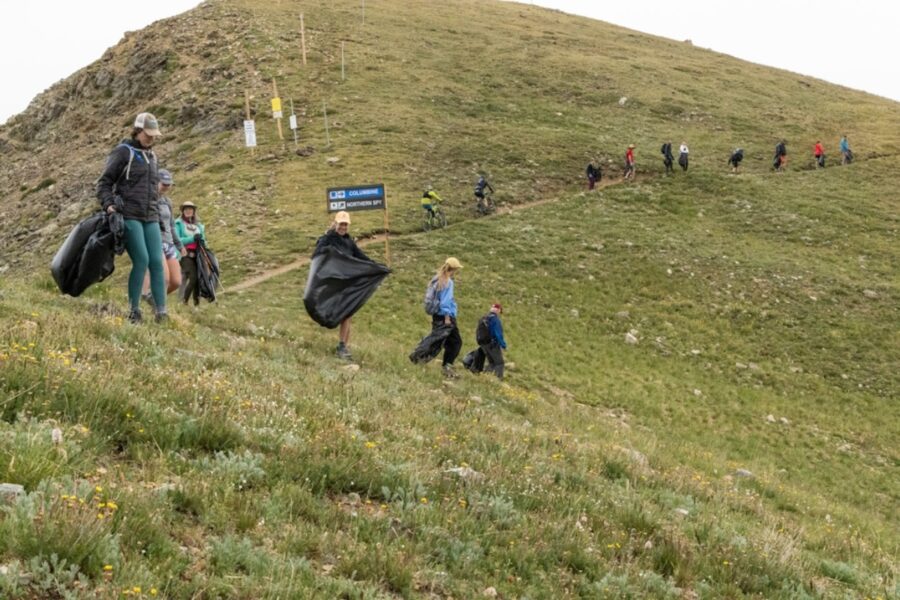 Scenic view of hikers on a trail at Arapahoe Basin, surrounded by lush greenery and majestic mountain peaks.
