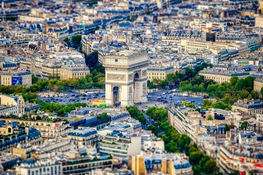 Aerial view of Arc de Triomphe, Paris, surrounded by traffic and classic architecture at sunset.