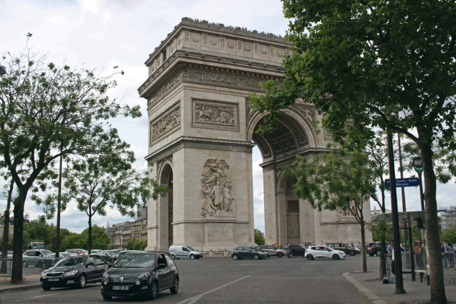 Arc de Triomphe Paris, historic monument surrounded by trees, traffic, and vibrant city life.
