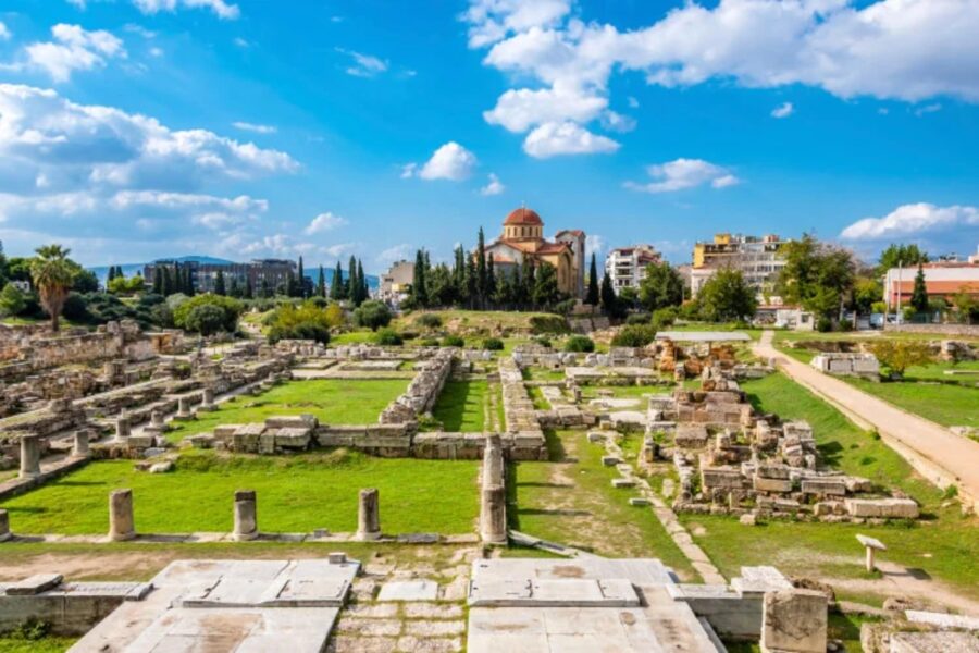 Kerameikos archaeological site ruins in Athens with ancient stone foundations and domed church skyline.