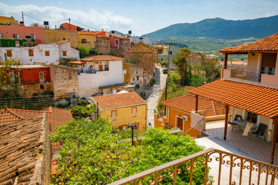 Vibrant view of the Archanes village in Crete, showcasing colorful buildings and lush greenery under a clear blue sky.