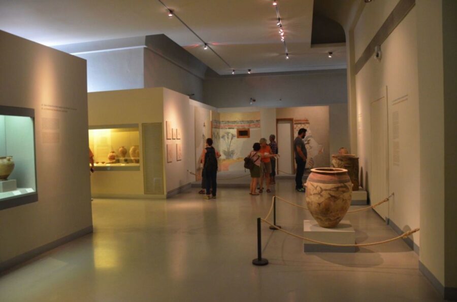 Ancient pottery exhibit in a modern museum interior with visitors exploring artifacts.