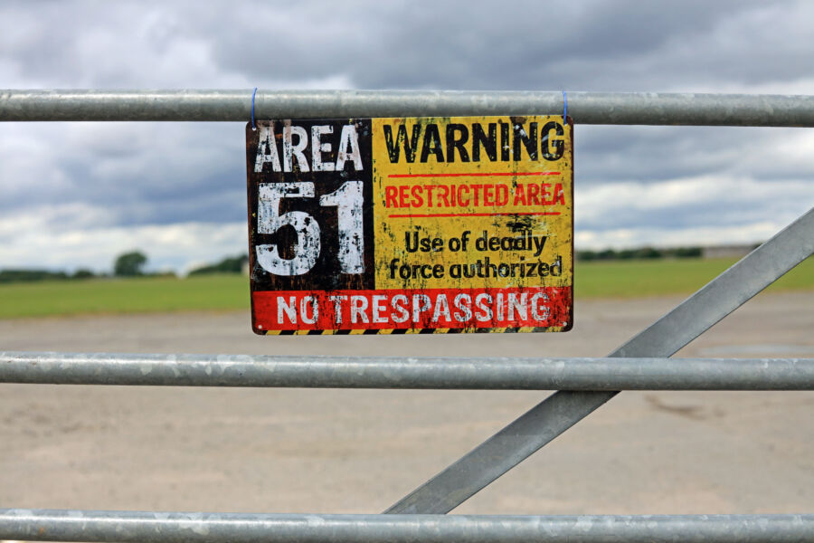 Vintage Area 51 warning sign displayed on a gate, indicating an extraterrestrial storage facility concept