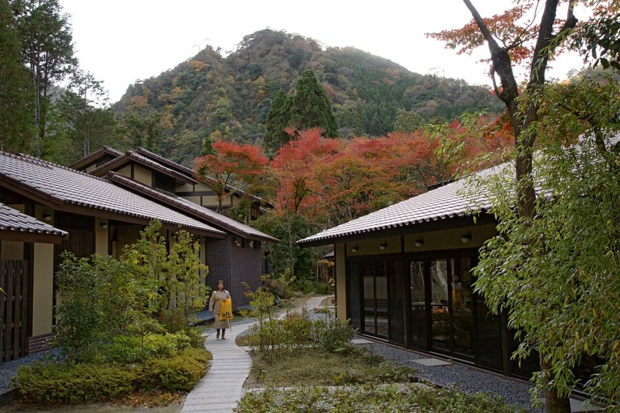 Person walking along a path between two buildings at Arimasansoh Goshobessho, surrounded by a serene atmosphere.