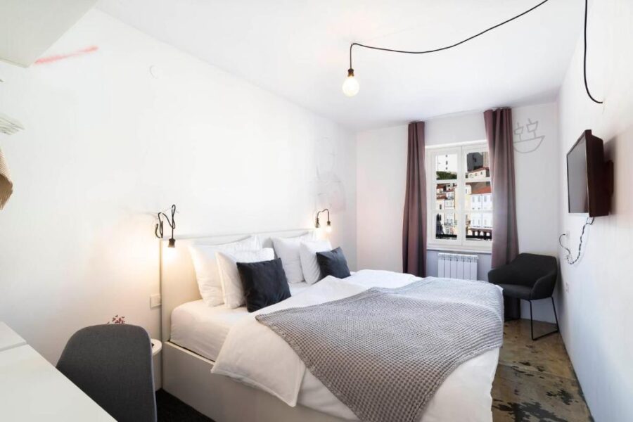 Interior of a bedroom at Art Hotel Tartini, Piran, Slovenia, showcasing a bed, desk, and a television.