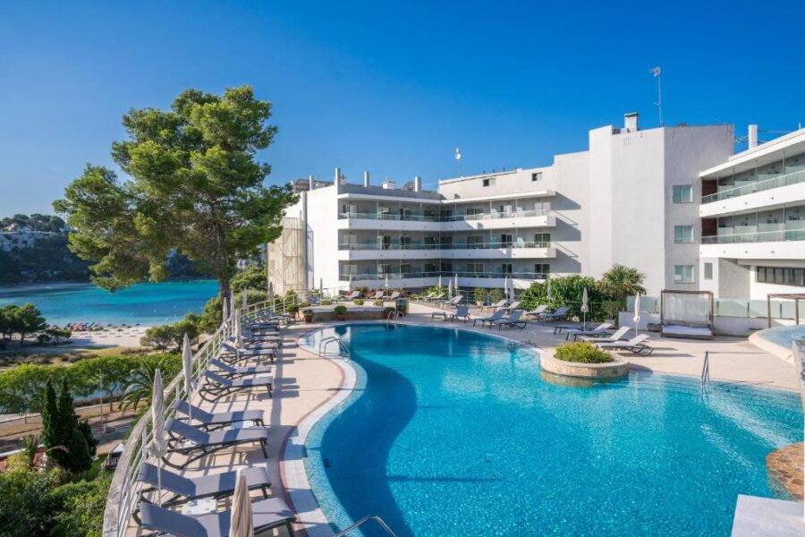 The pool at ARTIEM Audax, surrounded by lounge chairs and sun beds, invites relaxation under the sun.