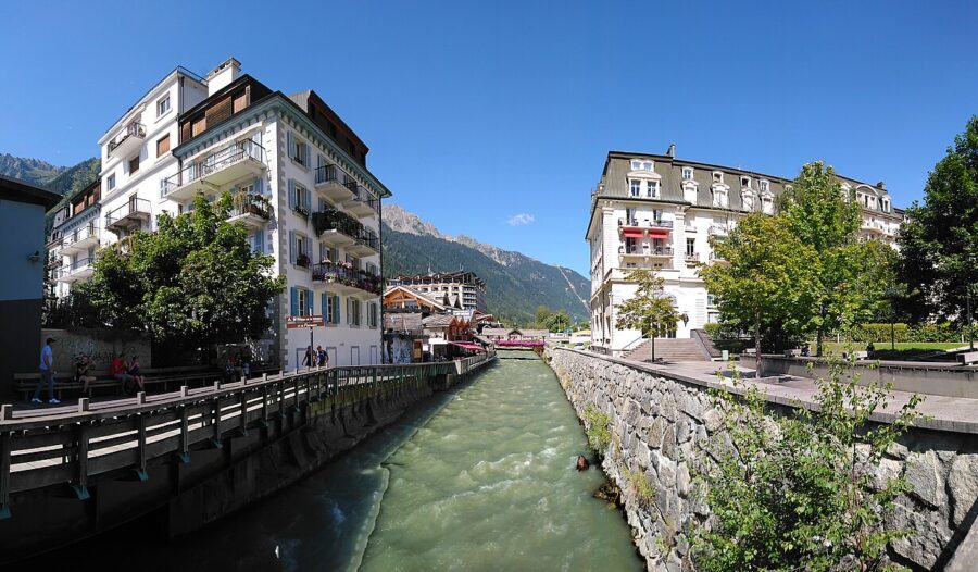 Arve River flowing through Chamonix, with buildings lining both sides of the waterway.
