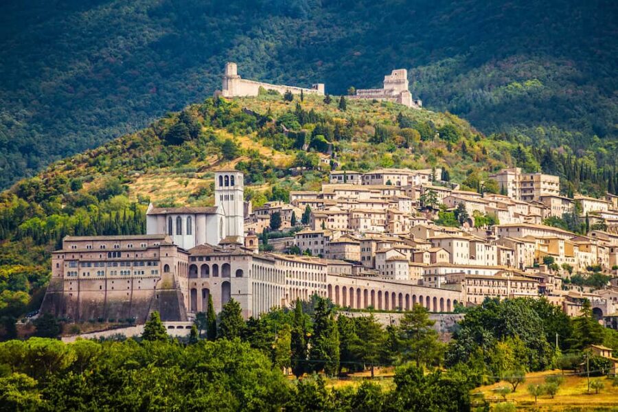 Panoramic view of Assisi, Umbria: historic architecture, lush greenery, ancient fortifications.
