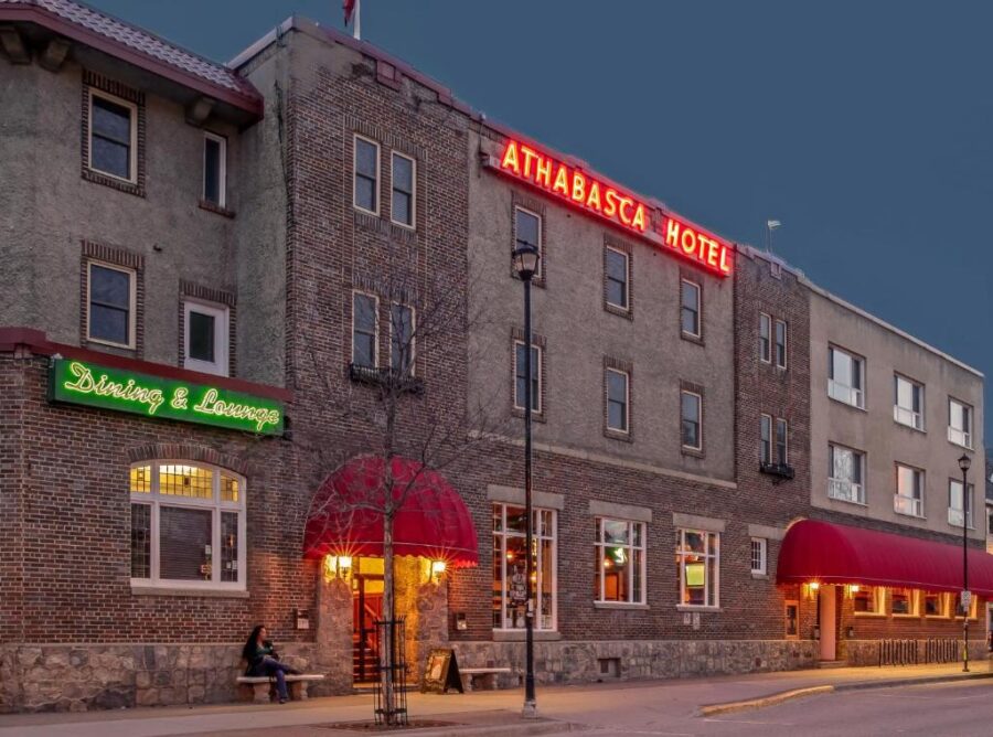 The Athabasca Hotel exterior illuminated at night, showcasing its architecture against a dark sky in Jasper, Canada.