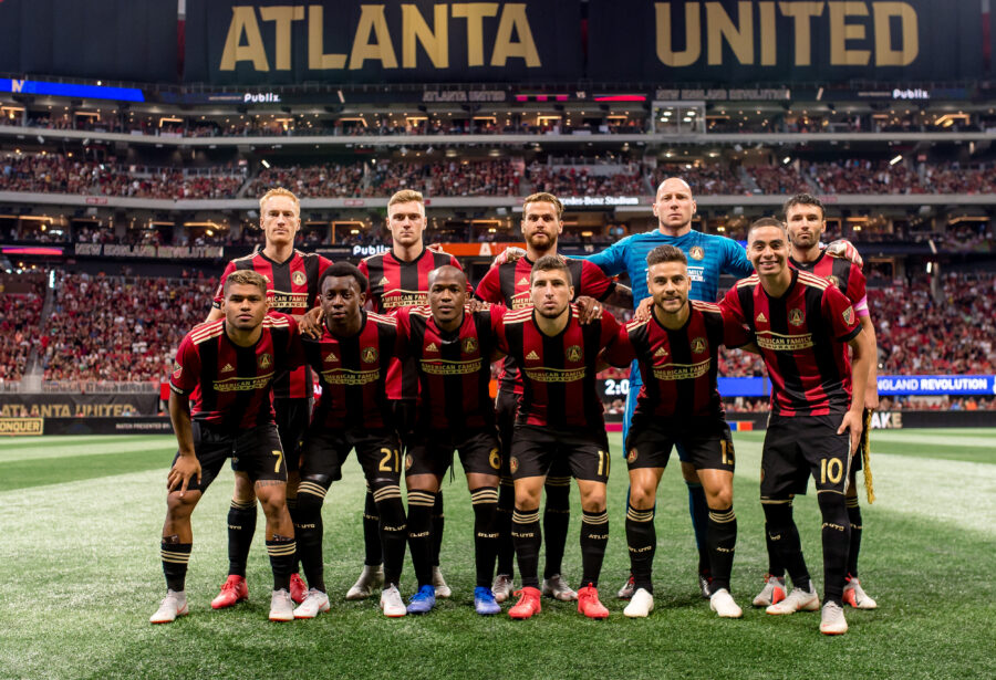 Atlanta United FC team photo in striped jerseys during an intense soccer match at evening.