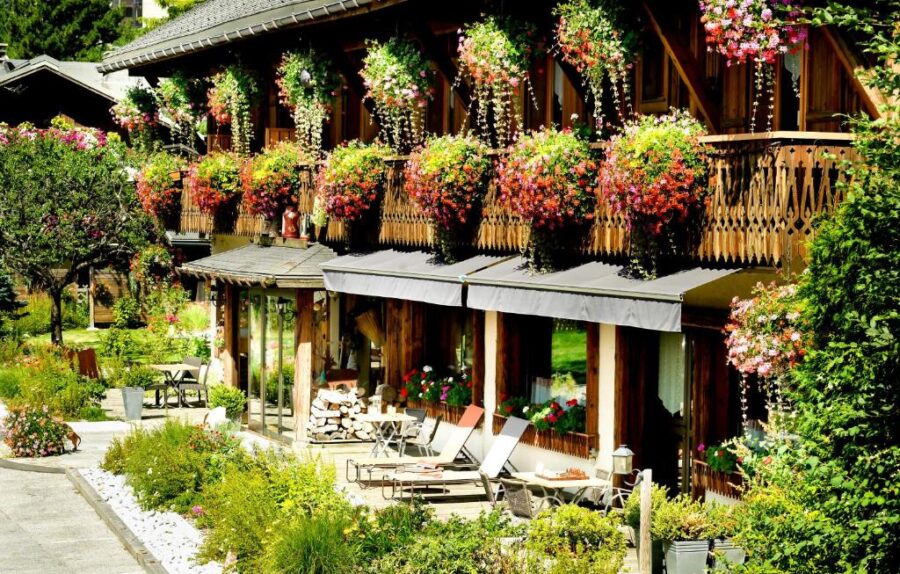 Auberge du Manoir in Chamonix, France, features balconies draped with vibrant flowers, adding charm to the hotel.
