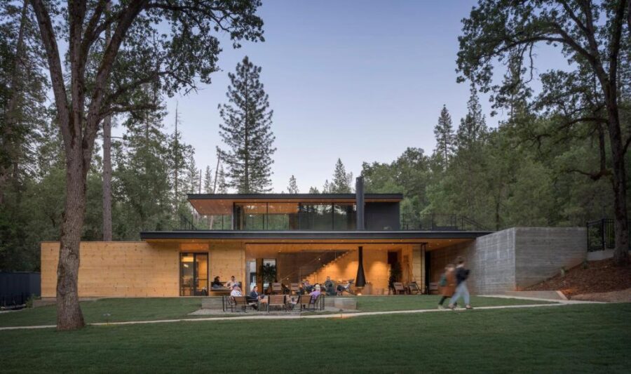 The house at AutoCamp Yosemite, nestled among trees with a large lawn, set in the scenic Yosemite National Park.