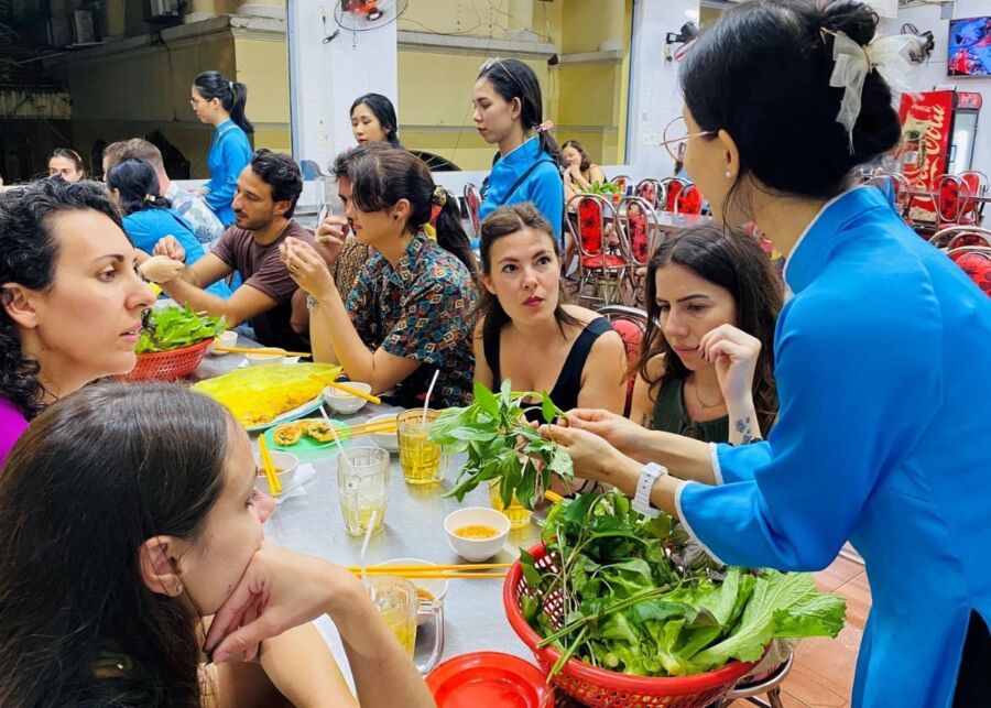 Diverse group seated at a table, sharing food and experiences on the award-winning Saigon Food Tour with GirlPower Drivers.