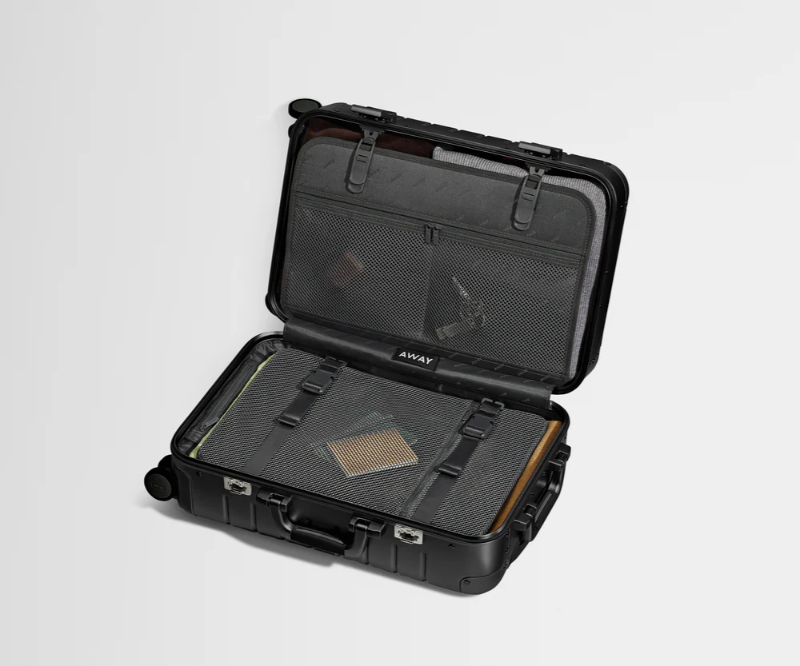 Black suitcase with a laptop compartment, containing a laptop, labeled as Away Aluminum Carry-On Storage.