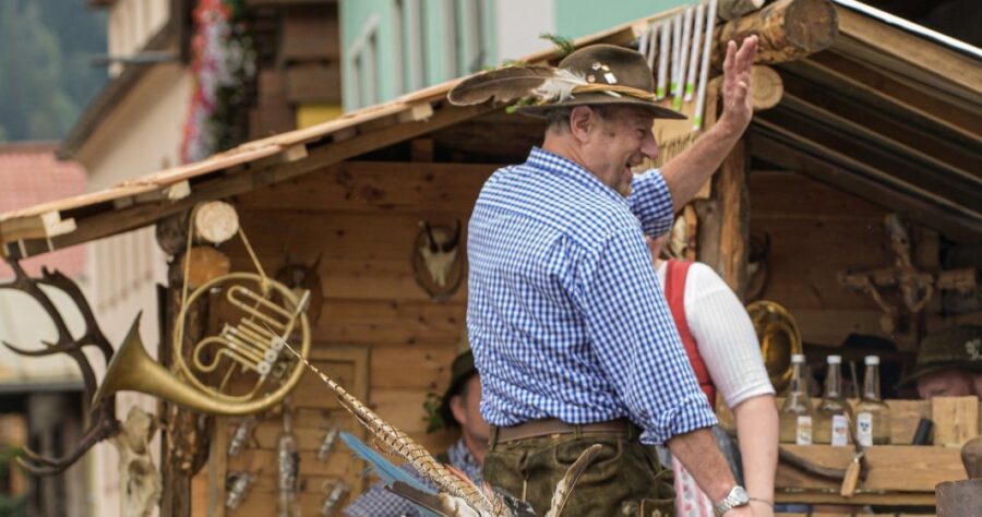 Man participating in the Bad Gastein Village Festival, with vibrant decorations and fellow festival-goers in the background.