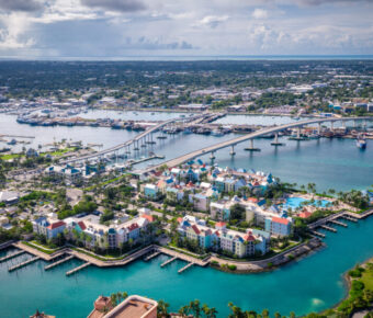 erial view of Nassau, Bahamas, showcasing vibrant blue waters, sandy beaches, and colorful buildings along the coastline.