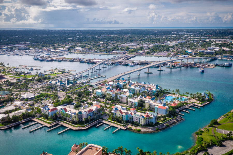 erial view of Nassau, Bahamas, showcasing vibrant blue waters, sandy beaches, and colorful buildings along the coastline.