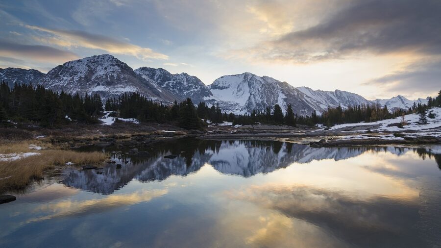 Sunset over Baker Lake reflects a stunning mountain range in Skoki Valley, creating a serene and picturesque landscape.