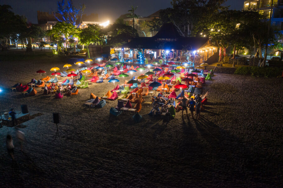 Bali beach at night illuminated by colorful lights, creating a vibrant and festive atmosphere along the shoreline