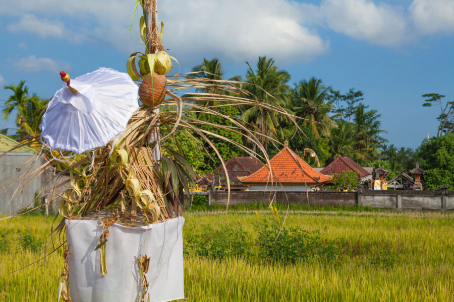 Hindu offering shrine decorated with flowers, part of Bali Penjor, situated in front of traditional Balinese houses