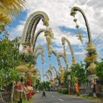Decorated Bali street with penjor, showcasing vibrant culture, traditional architecture, and tropical scenery.