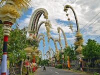 Decorated Bali street with penjor, showcasing vibrant culture, traditional architecture, and tropical scenery.