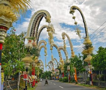 Decorated Bali street with penjor, showcasing vibrant culture, traditional architecture, and tropical scenery.