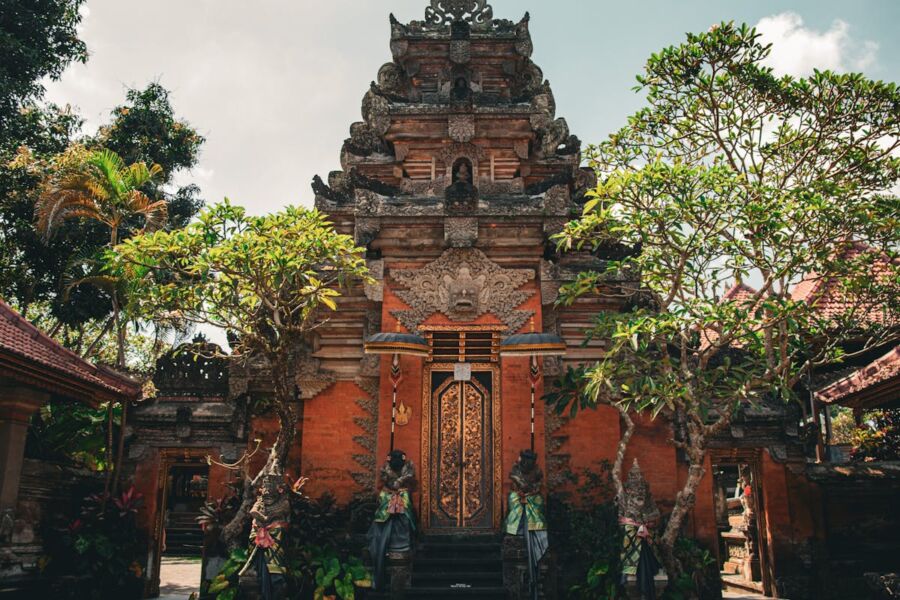 Traditional Balinese Ubud temple with ornate carvings, guardian statues, lush greenery, and spiritual ambiance.