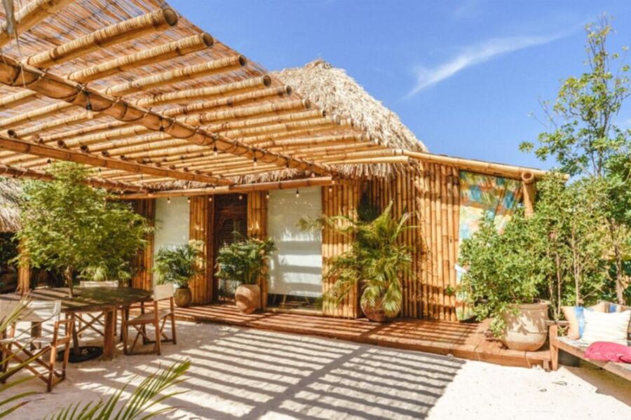Rustic bamboo bungalow with thatched roof, tropical greenery, and serene outdoor seating area.