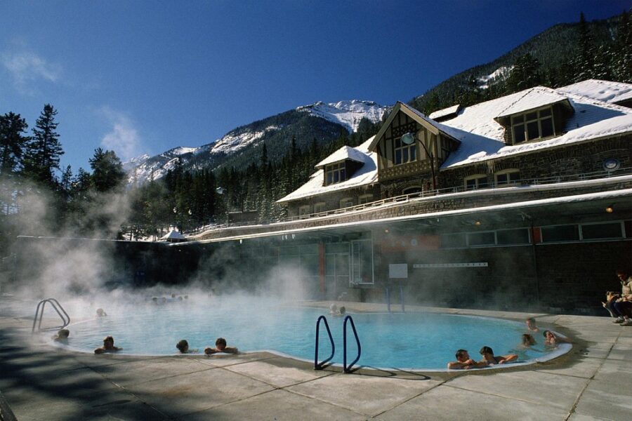 Guests relax and enjoy the warm waters of the Banff Upper Hot Springs at a scenic resort setting.
