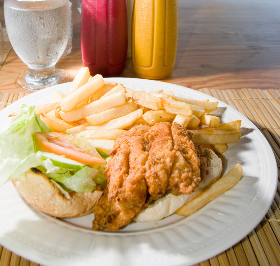 Close-up of a Barbados flying fish sandwich served with a side of crispy fries on a white plate