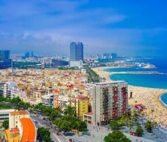 Aerial view of vibrant Barcelona coastal cityscape with beach, skyscrapers, and azure sea.