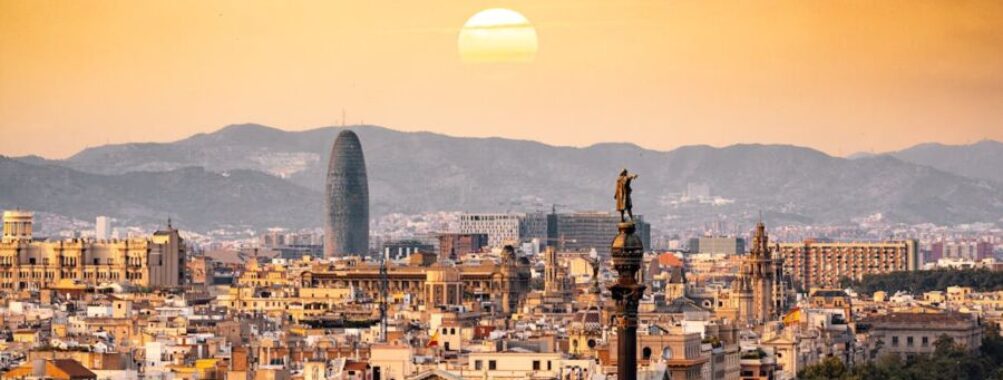 Barcelona cityscape at sunset with historical and modern architecture, blending culture and nature.