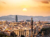 Barcelona cityscape at sunset with historical and modern architecture, blending culture and nature.