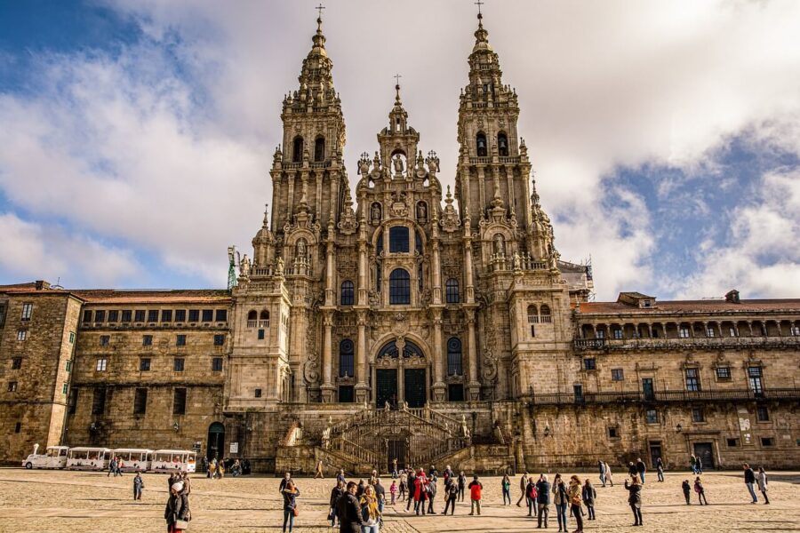 Baroque Cathedral of Santiago de Compostela façade with tourists in lively plaza.