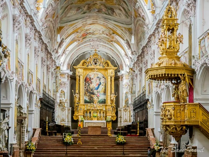 Ornate church interior showcasing lavish altar, frescoes, and pulpit in Baroque style.