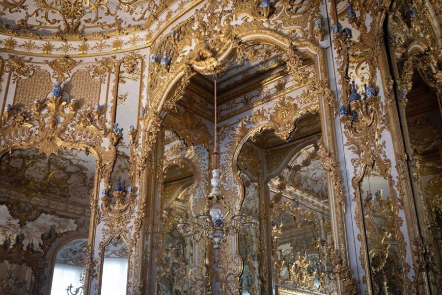 Luxurious Baroque interior with gold embellishments, mirrors, chandelier, and intricate design elements.