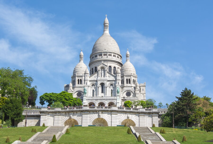 The Basilica of Sacre Coeur, a stunning white domed church, stands majestically atop Montmartre in Paris, France.