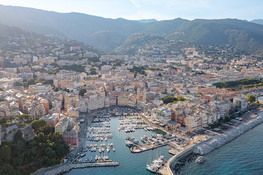 Aerial view of Bastia, Corsica, France, showcasing the coastline, cityscape, and surrounding hills.