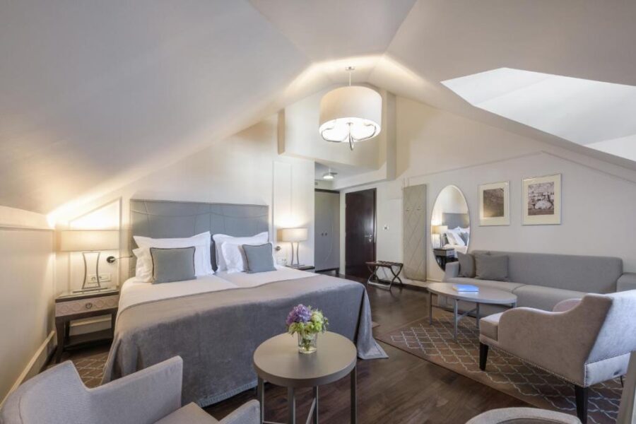 Interior of a bedroom at Bastion Heritage Hotel in Zadar, showcasing a bed, couch, and a small table.