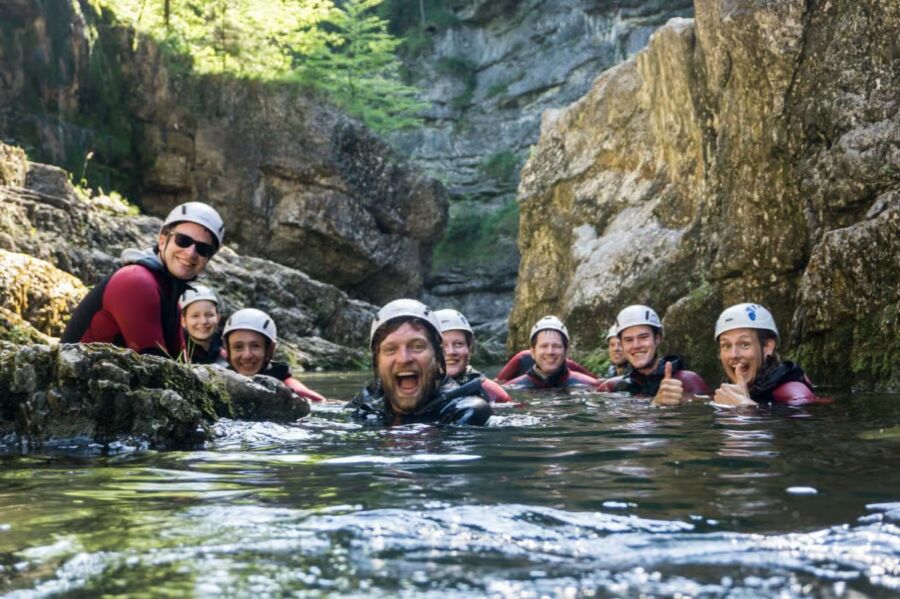 Participants in helmets engage in Bavaria canyoning, splashing in the water, highlighting a fun beginner experience.
