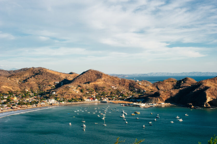 Colorful panoramic view of San Juan del Sur bay, Nicaragua, featuring lush hills and sparkling blue waters